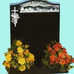 Black headstone with carved country scene
